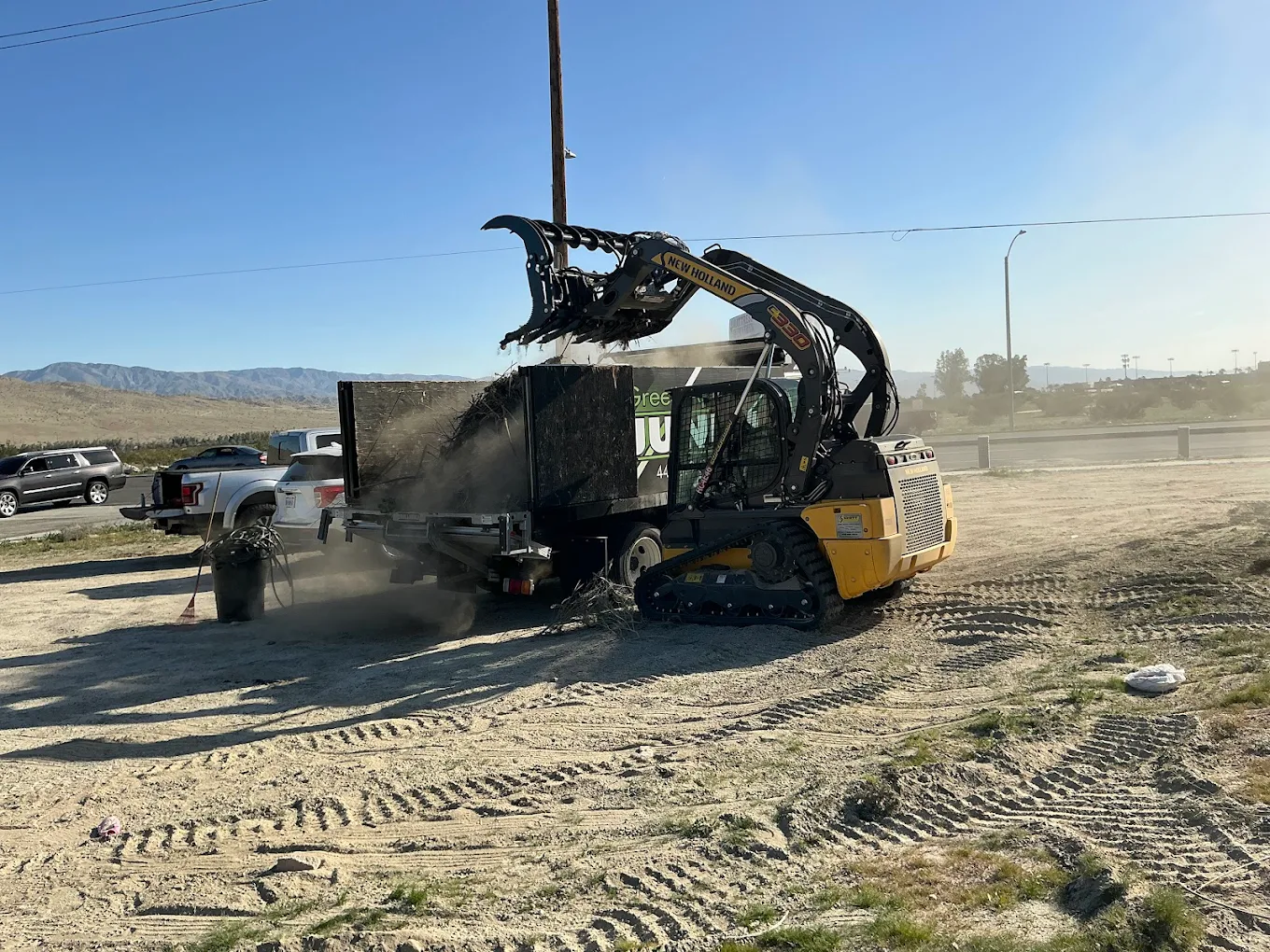 Skid steer loading debris into junk trailer at desert job site