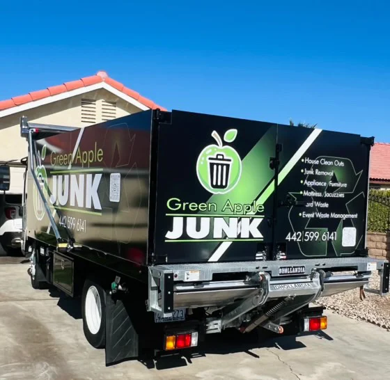 Green Apple Junk branded truck side view — services listed: house clean outs, junk removal, appliance/furniture, mattress/jacuzzis, yard waste, event waste management